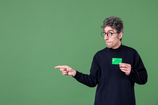 Retrato de hombre genio con tarjeta de crédito verde en foto de estudio pared verde