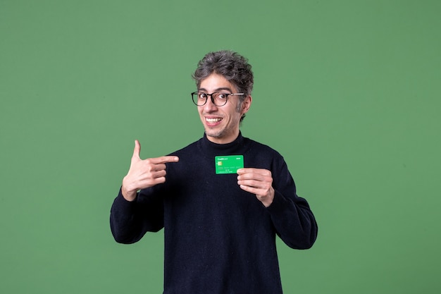 Retrato de hombre genio con tarjeta de crédito verde en la pared verde