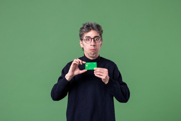 Retrato de hombre genio con tarjeta de crédito verde en la pared verde