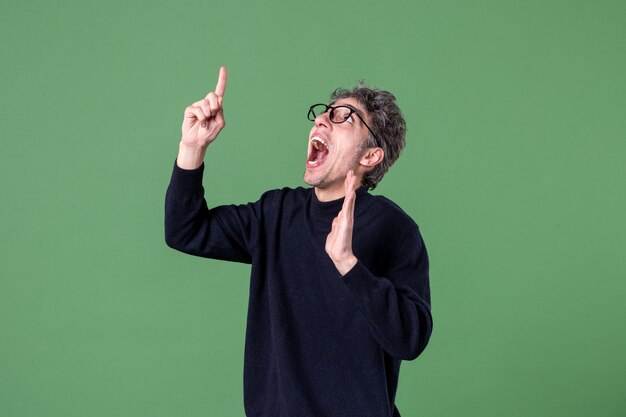 Retrato de hombre genio vestido casualmente en foto de estudio apuntando a la pared verde