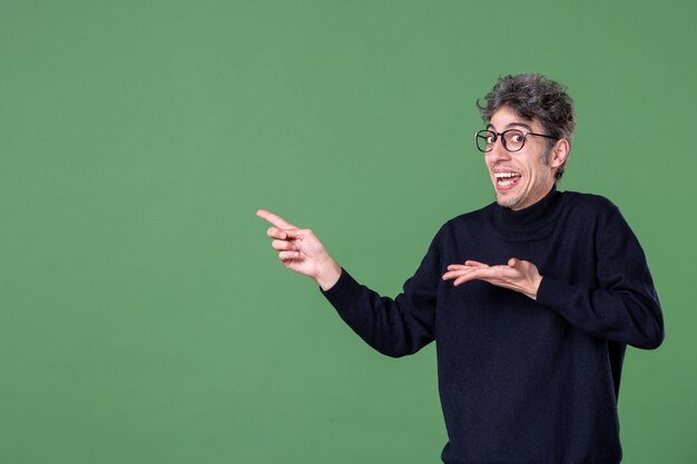 Retrato de hombre genio vestido casualmente en foto de estudio en la pared verde