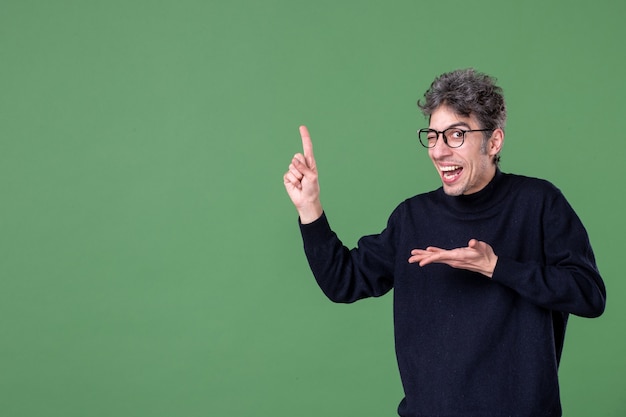 Retrato de hombre genio vestido casualmente en foto de estudio en la pared verde