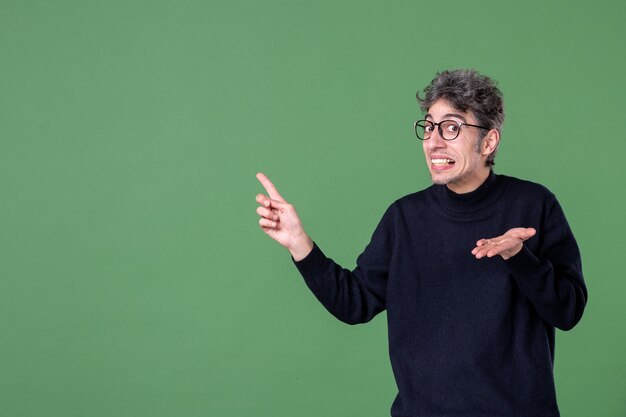 Retrato de hombre genio vestido casualmente en foto de estudio en la pared verde