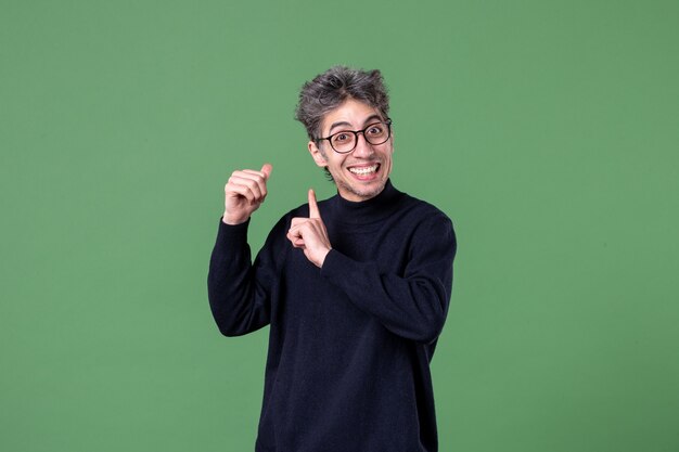 Retrato de hombre genio vestido casualmente en foto de estudio en la pared verde