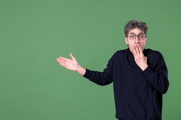 Foto gratuita retrato de hombre genio vestido casualmente en foto de estudio en la pared verde