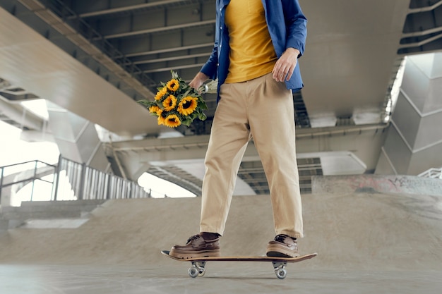 Foto gratuita retrato de hombre con girasoles en monopatín