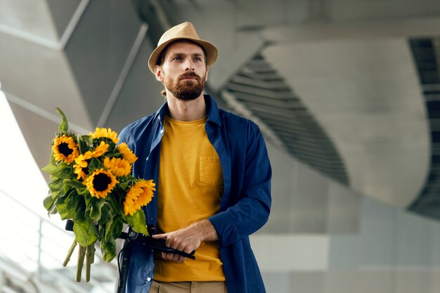 Retrato de hombre con girasoles en scooter eléctrico al aire libre