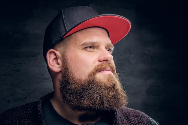 Retrato de un hombre gordo y barbudo vestido con una chaqueta y una gorra de béisbol.