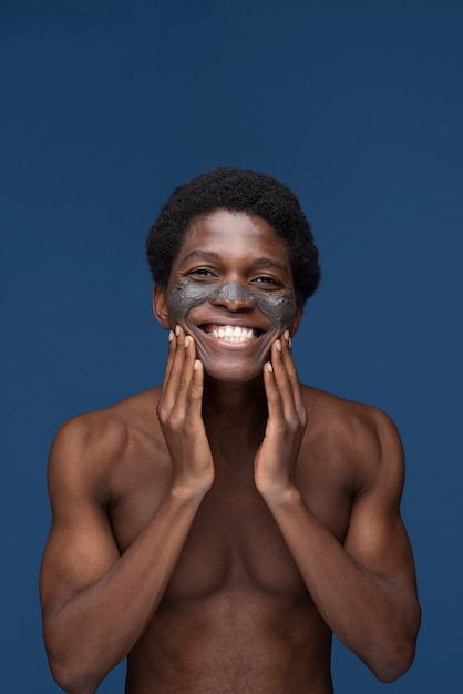 Retrato de un hombre guapo aplicando mascarilla de carbón