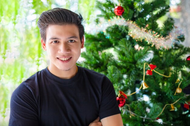 Retrato hombre guapo con árbol de navidad