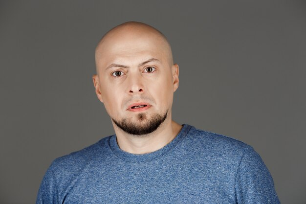 Retrato de hombre guapo en camisa gris sobre pared oscura