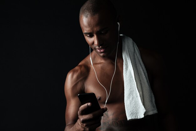 Retrato de hombre guapo deportivo con teléfono móvil después del entrenamiento