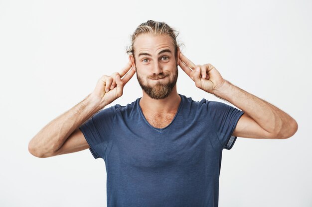 Retrato de hombre guapo divertido con barba haciendo caras tontas y gesticulando con las manos