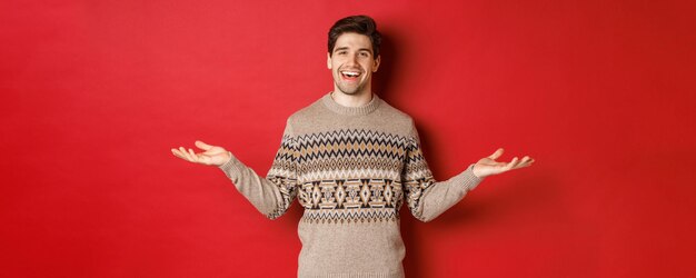 Retrato de un hombre guapo feliz celebrando las vacaciones de año nuevo usando un suéter de navidad esparcido han