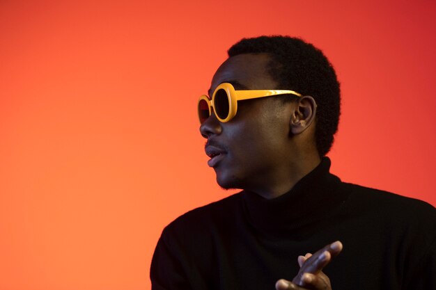 Foto gratuita retrato de hombre guapo con gafas de sol sobre fondo naranja