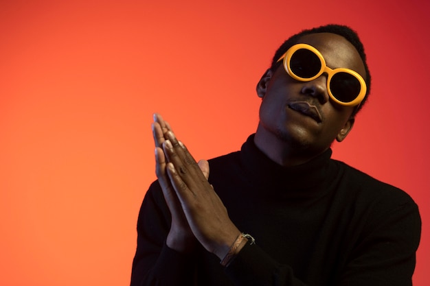 Foto gratuita retrato de hombre guapo con gafas de sol sobre fondo naranja