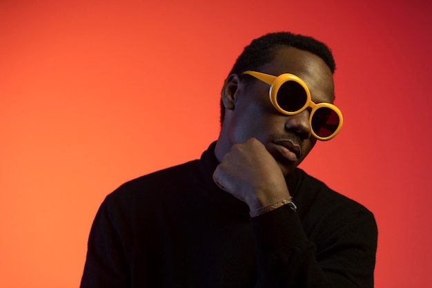 Retrato de hombre guapo con gafas de sol sobre fondo naranja