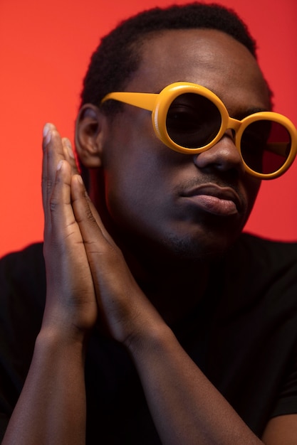 Retrato de hombre guapo con gafas de sol sobre fondo naranja