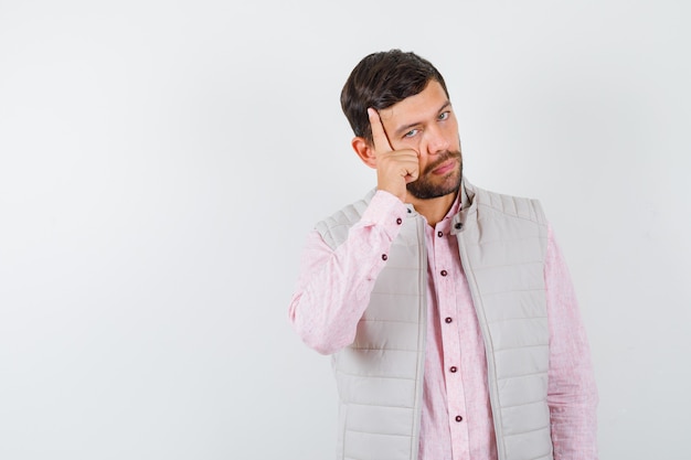 Retrato de hombre guapo manteniendo la mano en la cabeza en chaleco, camisa y mirando confiado