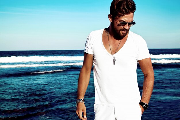 Retrato de hombre guapo modelo vistiendo ropa blanca posando en mar azul