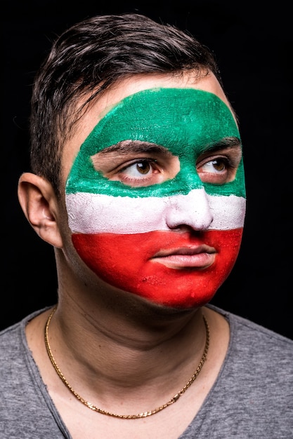 Retrato de hombre guapo rostro partidario fan del equipo nacional de Irán con cara de bandera pintada aislado sobre fondo negro. Fans de las emociones.