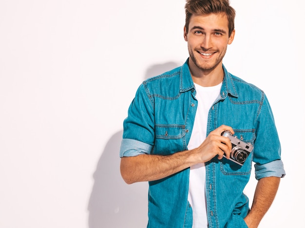 Retrato de hombre guapo sonriente vistiendo ropa de verano jeans. Modelo masculino con cámara de fotos vintage.