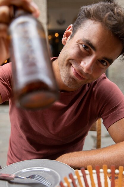 Retrato de hombre guapo viajero sosteniendo una botella de cerveza