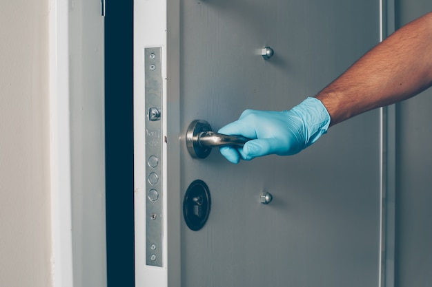 Foto gratuita retrato de un hombre en la habitación abriendo la puerta con las manos en guantes