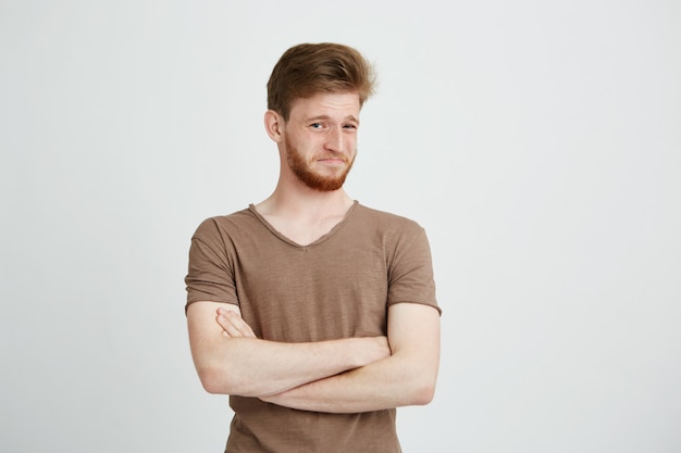 El retrato del hombre hermoso joven con la barba con desprecio cruzó los brazos.