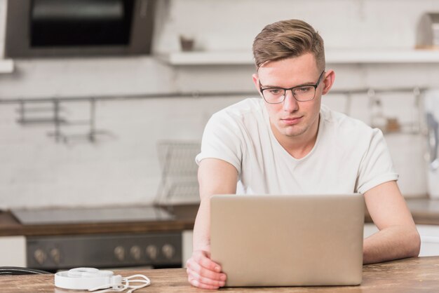 Retrato de un hombre hermoso joven que mira la computadora portátil