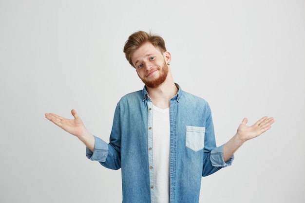 Retrato del hombre hermoso joven que sonríe encogiéndose de hombros.