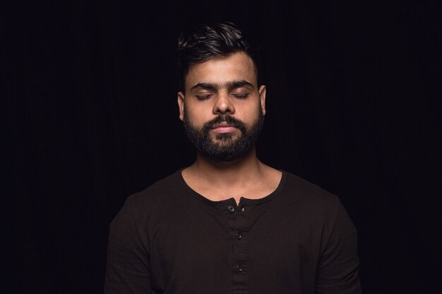 Retrato de hombre joven aislado sobre fondo negro de estudio de cerca. Photoshot de emociones reales del modelo masculino con los ojos cerrados. Considerado. Concepto de expresión facial, naturaleza humana y emociones.