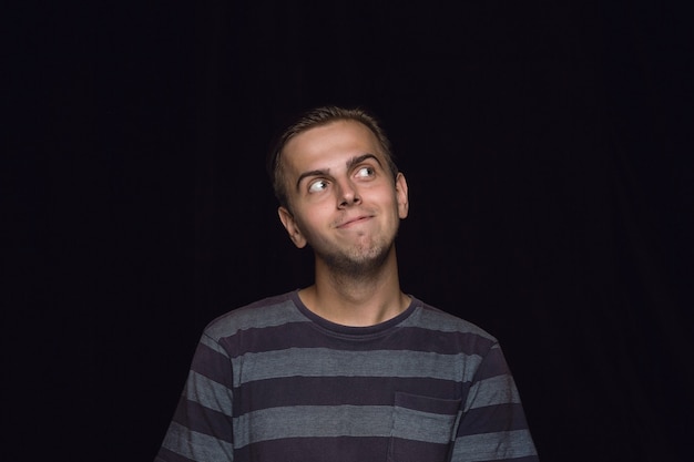 Retrato de hombre joven aislado sobre fondo negro de estudio de cerca.