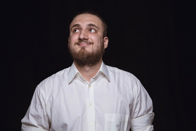 Retrato de hombre joven aislado sobre fondo negro de estudio de cerca.