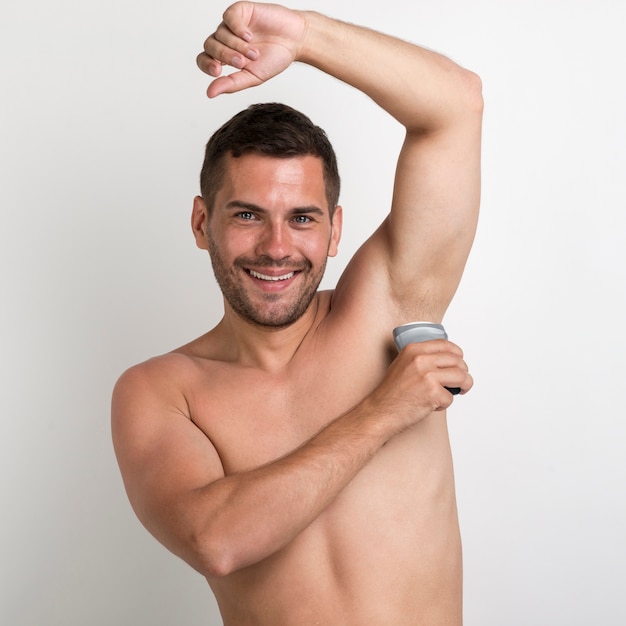 Foto gratuita retrato de hombre joven aplicando roll en desodorante mirando a la cámara