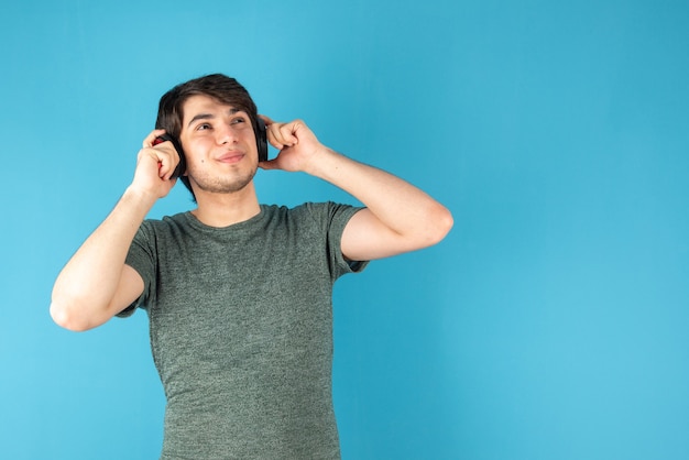 Retrato de hombre joven con auriculares en la cabeza contra el azul.