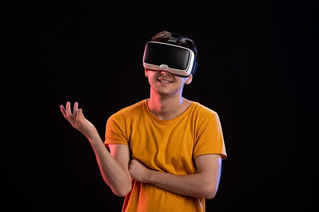 Retrato de hombre joven con auriculares vr en la pared oscura