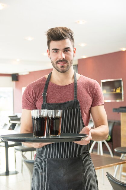 Retrato de hombre joven con bandeja en el restaurante