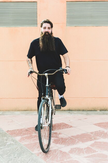 Retrato de un hombre joven con barba larga montando la bicicleta