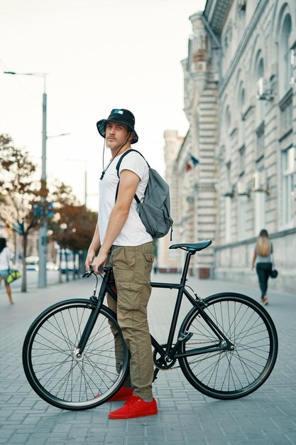 Retrato de hombre joven caminando con bicicleta cuidadosamente clásica