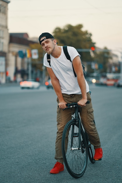 Foto gratuita retrato de hombre joven caminando cuidadosamente con bicicleta clásica