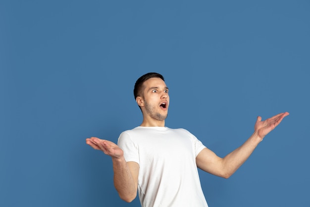 Retrato de hombre joven caucásico en la pared azul