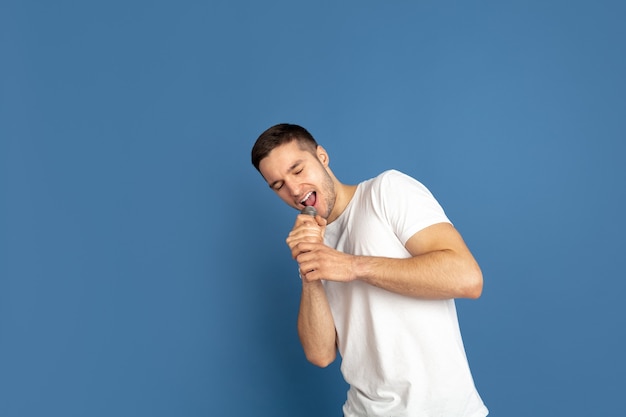 Retrato de hombre joven caucásico en la pared azul