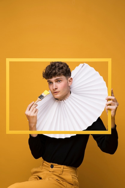 Retrato de hombre joven en un escenario amarillo detrás de un marco