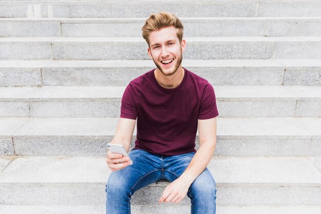 Retrato de un hombre joven feliz con teléfono móvil