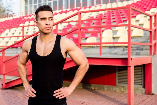 Retrato de un hombre joven fitness masculino de pie delante de la grada