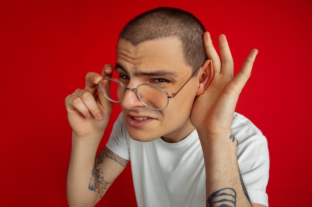 Retrato de hombre joven con gafas aislado en la pared roja del estudio