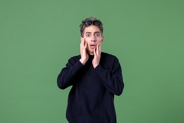 Retrato de hombre joven genio vestido casualmente con expresión de sorpresa en foto de estudio sobre superficie verde