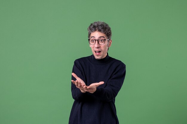 Retrato de hombre joven genio vestido casualmente en foto de estudio feliz en la pared verde