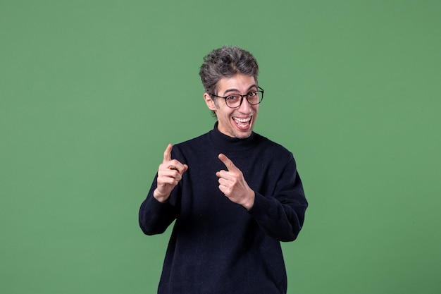 Foto gratuita retrato de hombre joven genio vestido casualmente en foto de estudio feliz en la pared verde